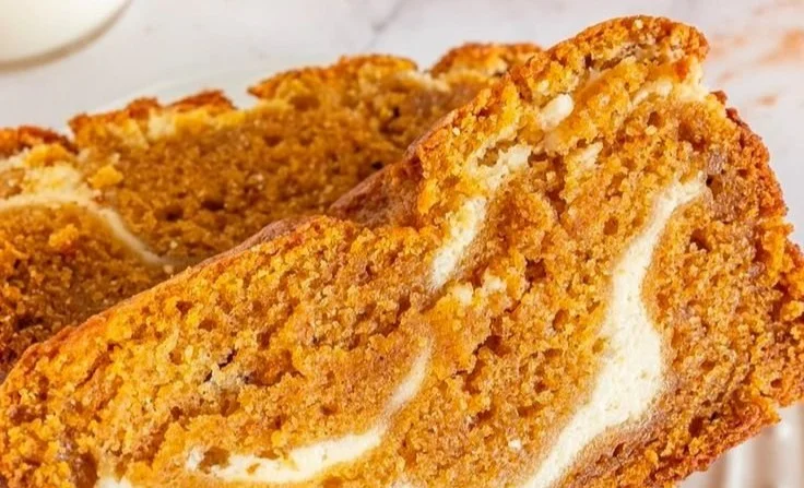 Slice of moist pumpkin bread with cream cheese frosting on a plate.