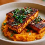 Smoky tofu steak served with creamy mashed sweet potatoes on a plate
