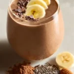 Choco-Banana Protein Smoothie in a glass topped with banana slices and chocolate drizzle