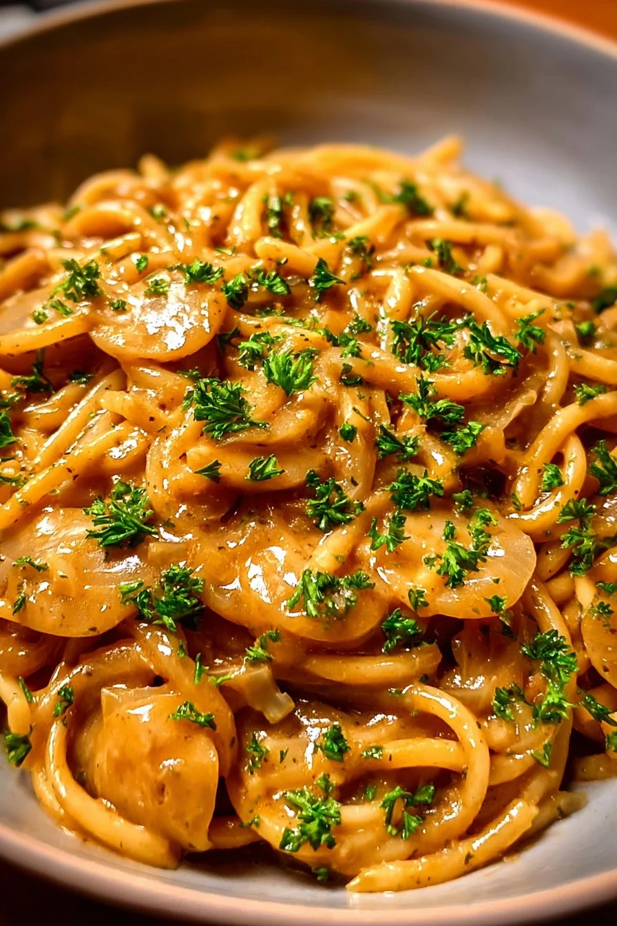 Delicious easy French onion pasta served in a bowl with cheese topping.