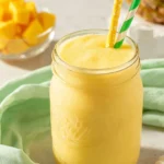 Delicious Pineapple Orange Smoothie in a glass with tropical fruits.